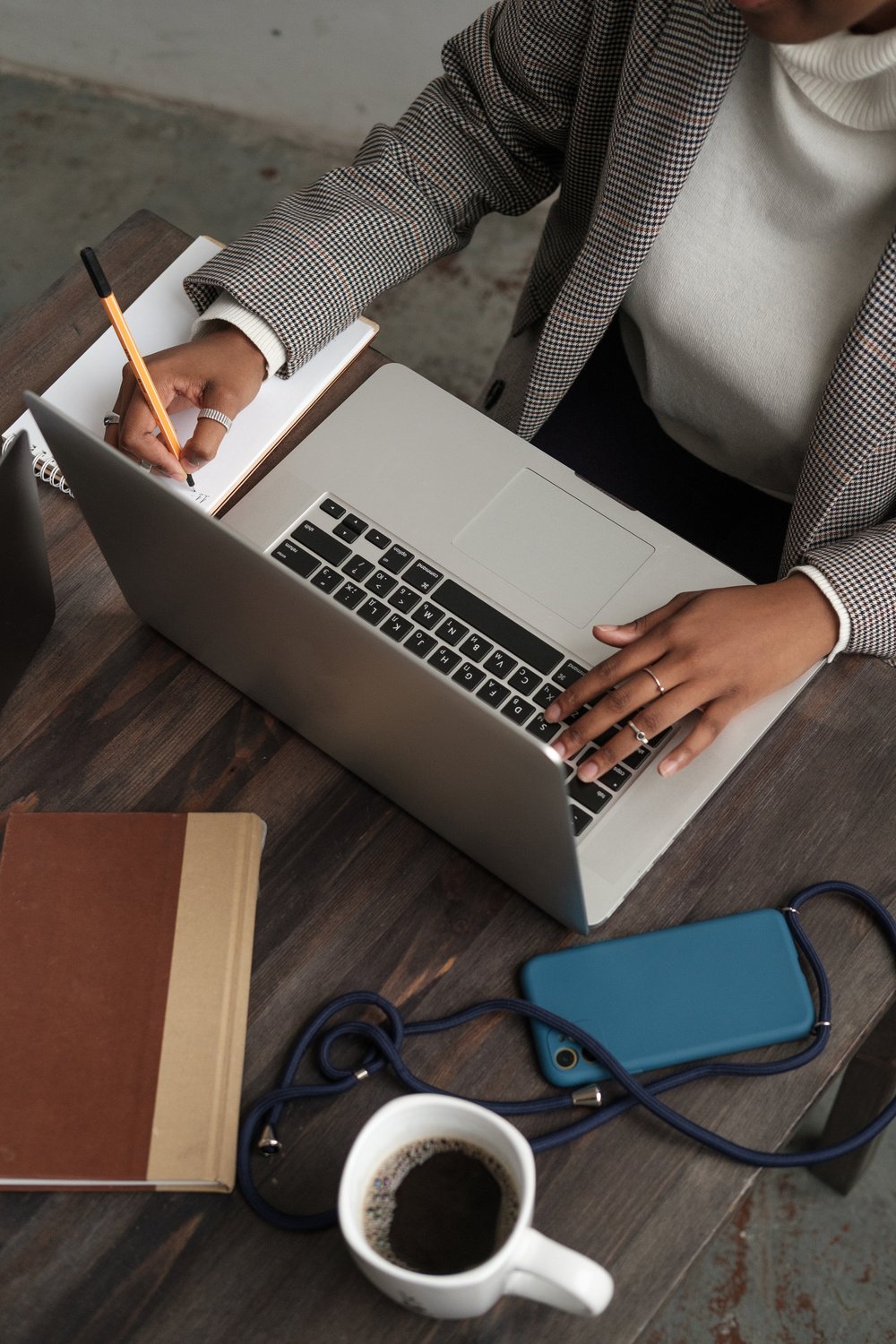 Businesswoman Writing Notes While Using Laptop